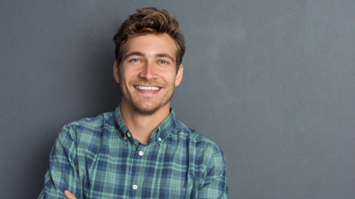 Young man smiling confidently, representing a patient satisfied with in-office nightguard treatment.