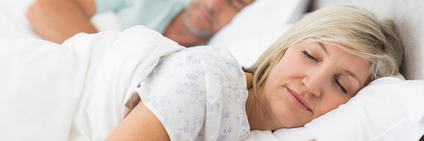 Middle-aged couple sleeping peacefully in bed, related to dental nightguard use